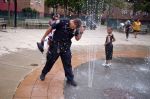 A New York City Police officer sticks his head in a fountain to quickly cool off during record heat waves affecting the country. Recent polls show more Americans believe in climate change.